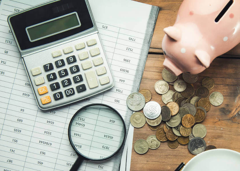 piggy bank, coins and a calculator on a table